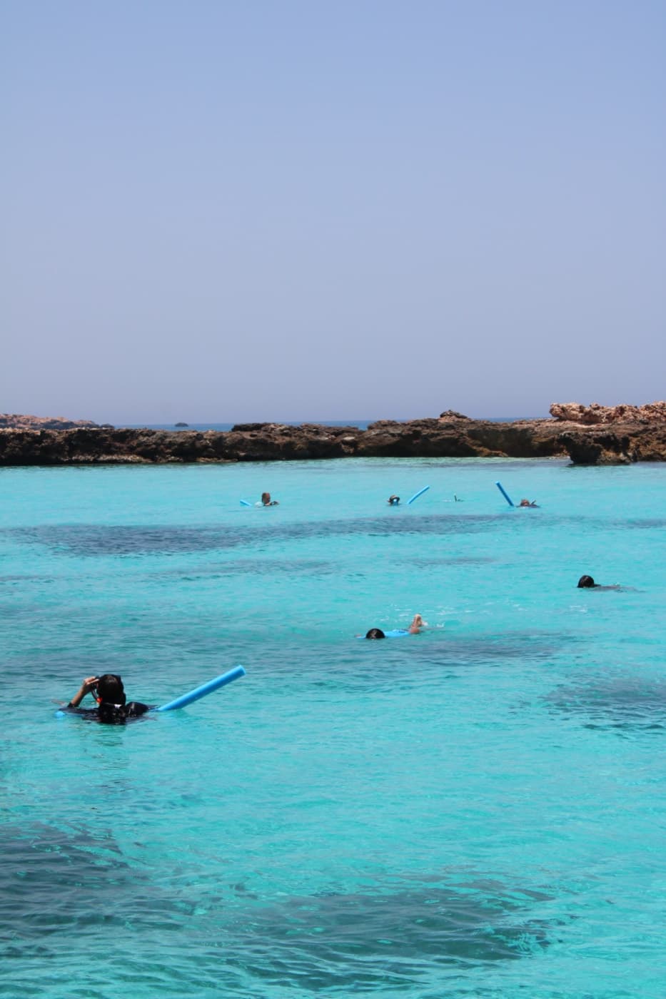 A group snorkelling in a calm turquoise lagoon at the Daymaniyat Islands on a full-day tour