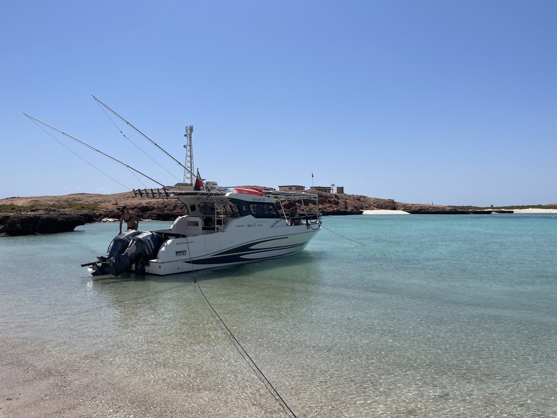 A Royal Marine Tours boat on calm turquoise water off the Muscat coast, ready for a fishing trip
