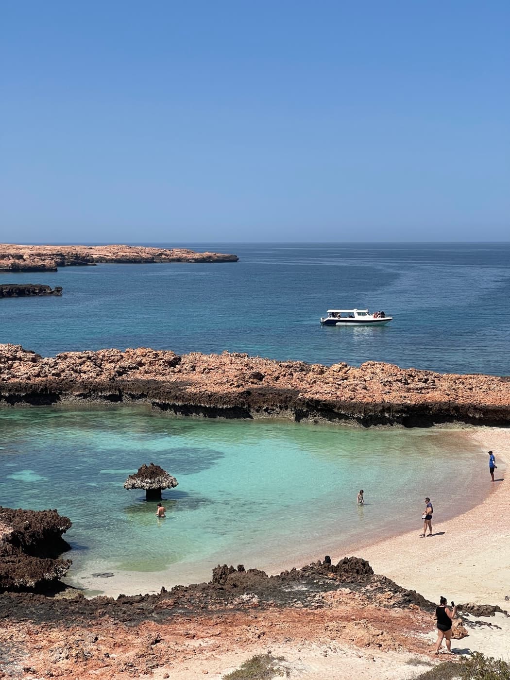 A Royal Marine Tours boat on calm water by a Daymaniyat island cove near Muscat